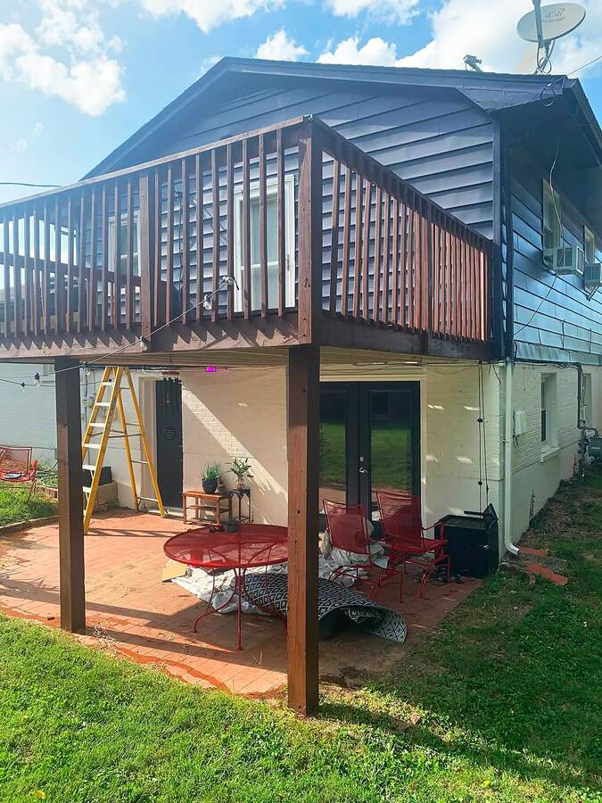 Elevated wooden deck with freshly stained railings over a brick patio